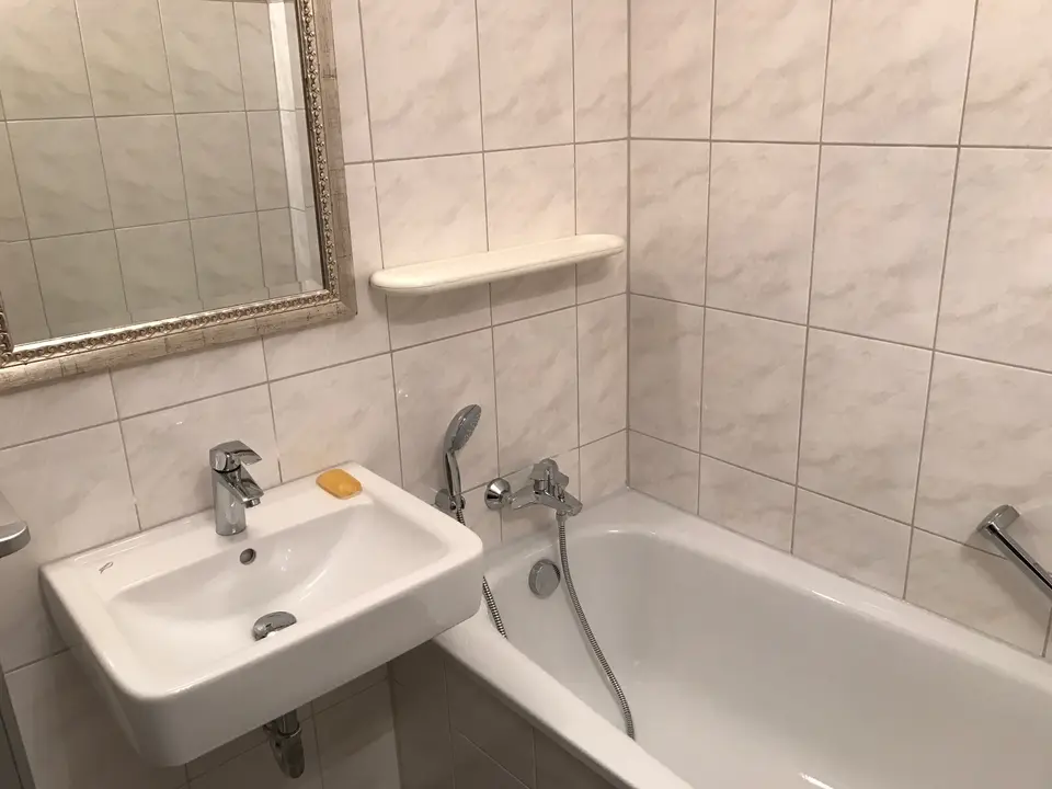 Badezimmer mit Badewanne, Waschbecken und hellen Fliesen