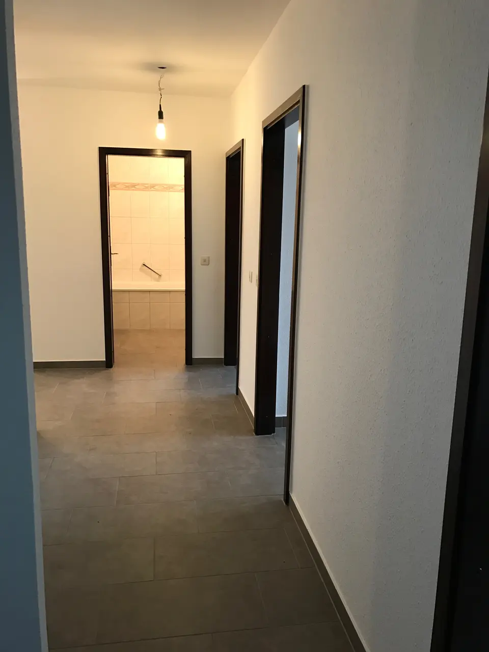 Flur mit modernen Fliesen und Blick in das Badezimmer
