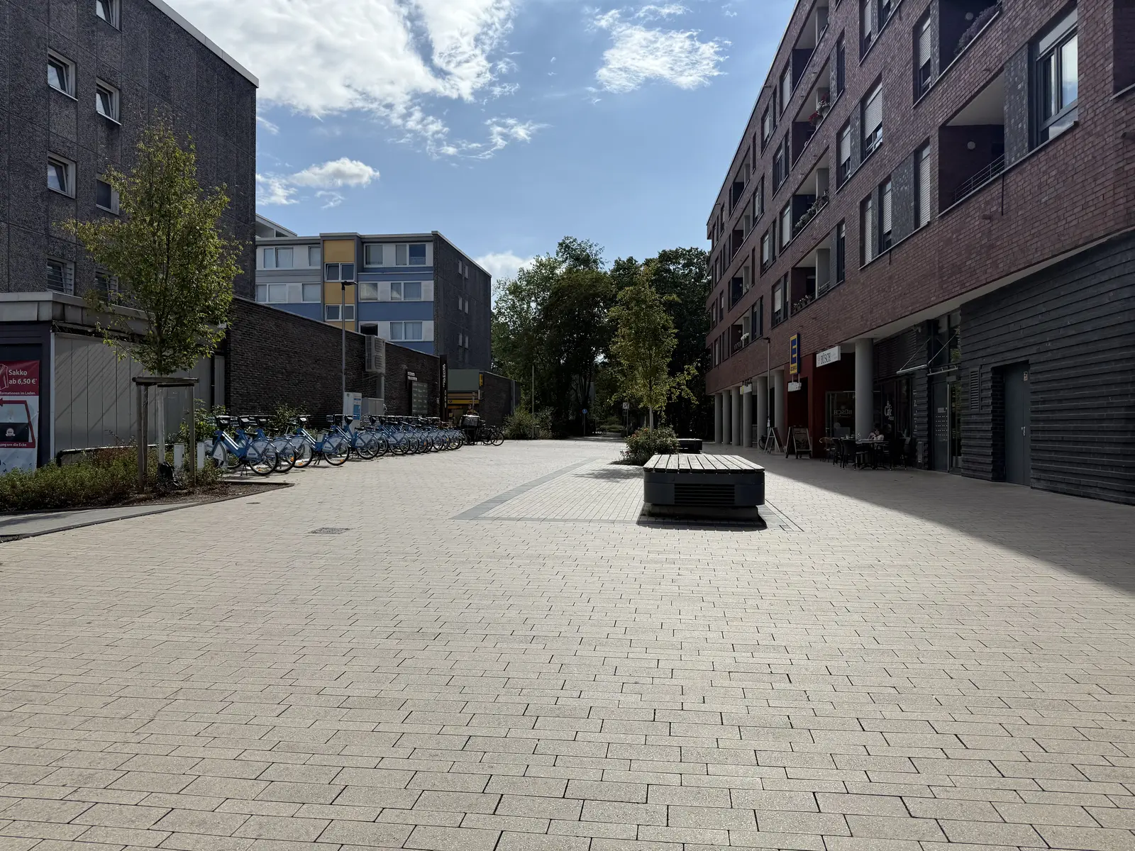 Fußgängerbereich im Sophie-Scholl-Quartier in Baumberg mit Leihrädern, Bäumen und Sitzbänken